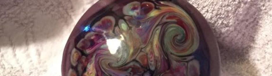 Close-up of a handmade glass bead with layered purple and silver details.