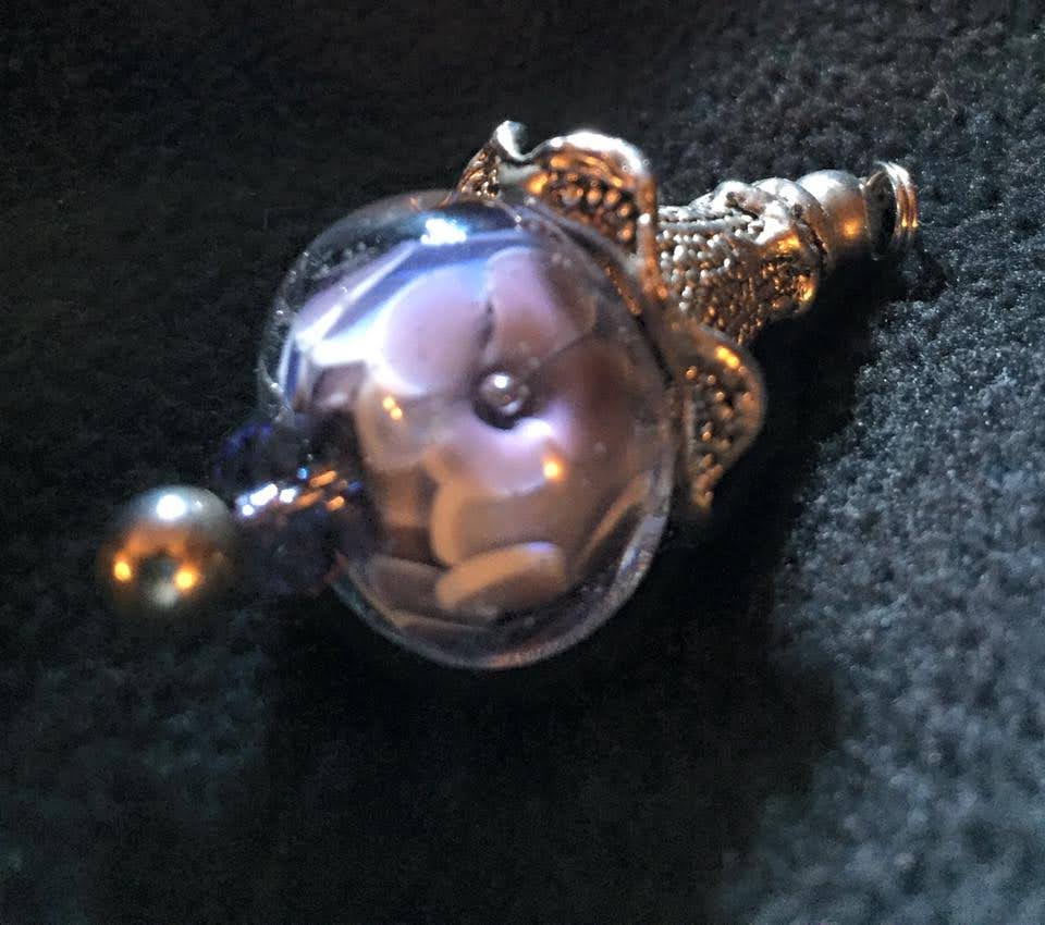 Encased purple floral bead strung as a pendant.